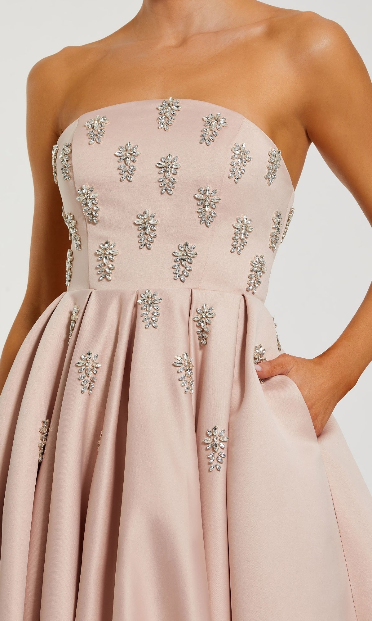 Pink strapless dress with floral embellishments on a neutral background